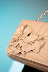 Women's leather shoulder bag in beige brown colour with quilting and leatherette flower brooch by JULKE. 