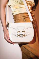 Womens leather shoulder bag in white colour with old horsebit buckle and metallic button flap by JULKE